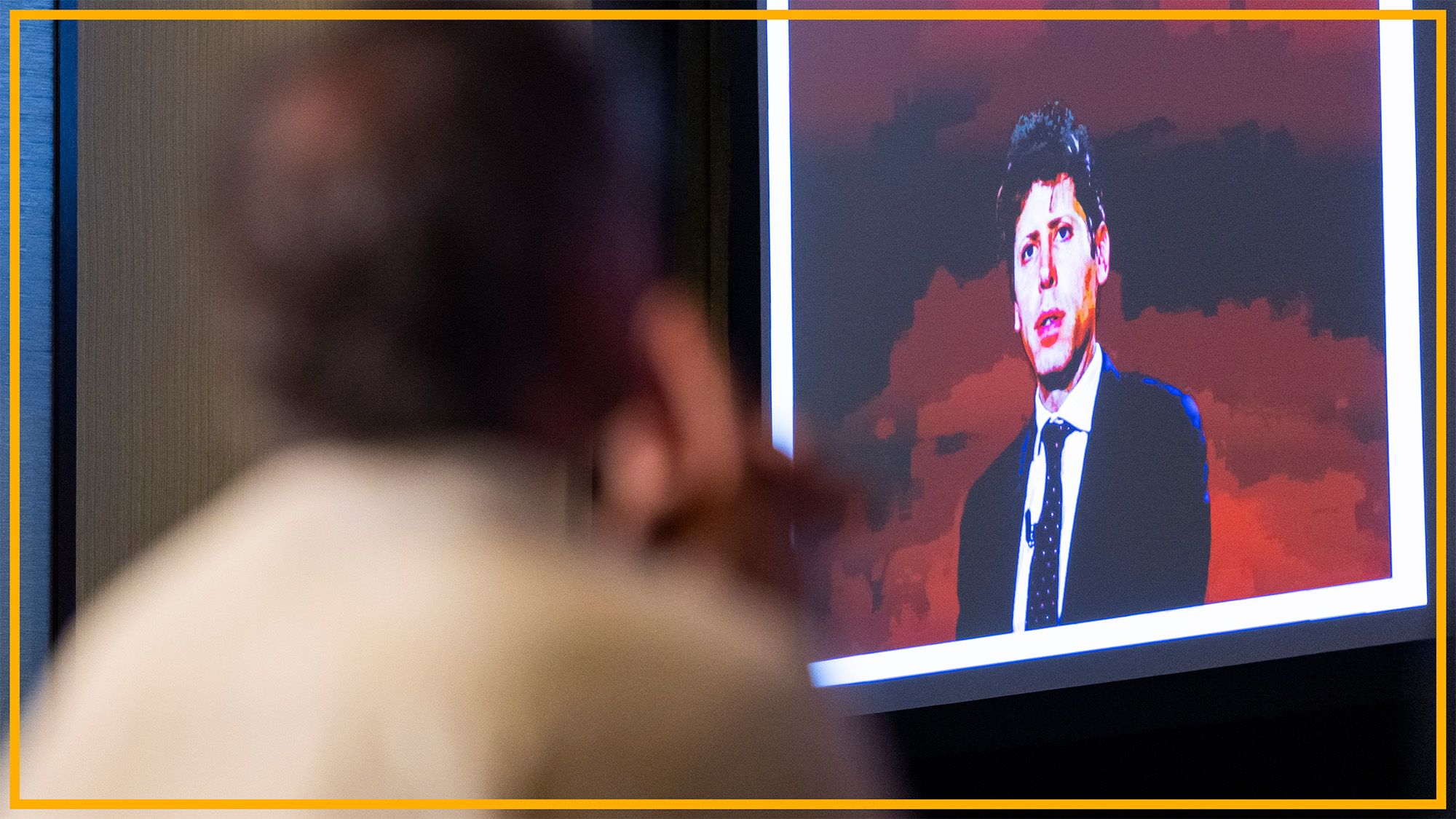 A man looks at a presentation with a man in front of a red background