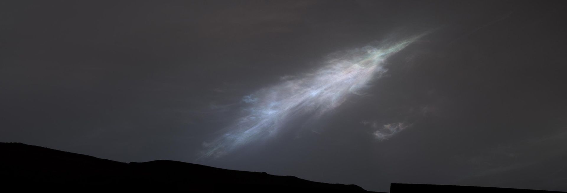 Une lumière blanche et brillante dans un ciel nocturne sombre avec un paysage en silhouette en dessous.