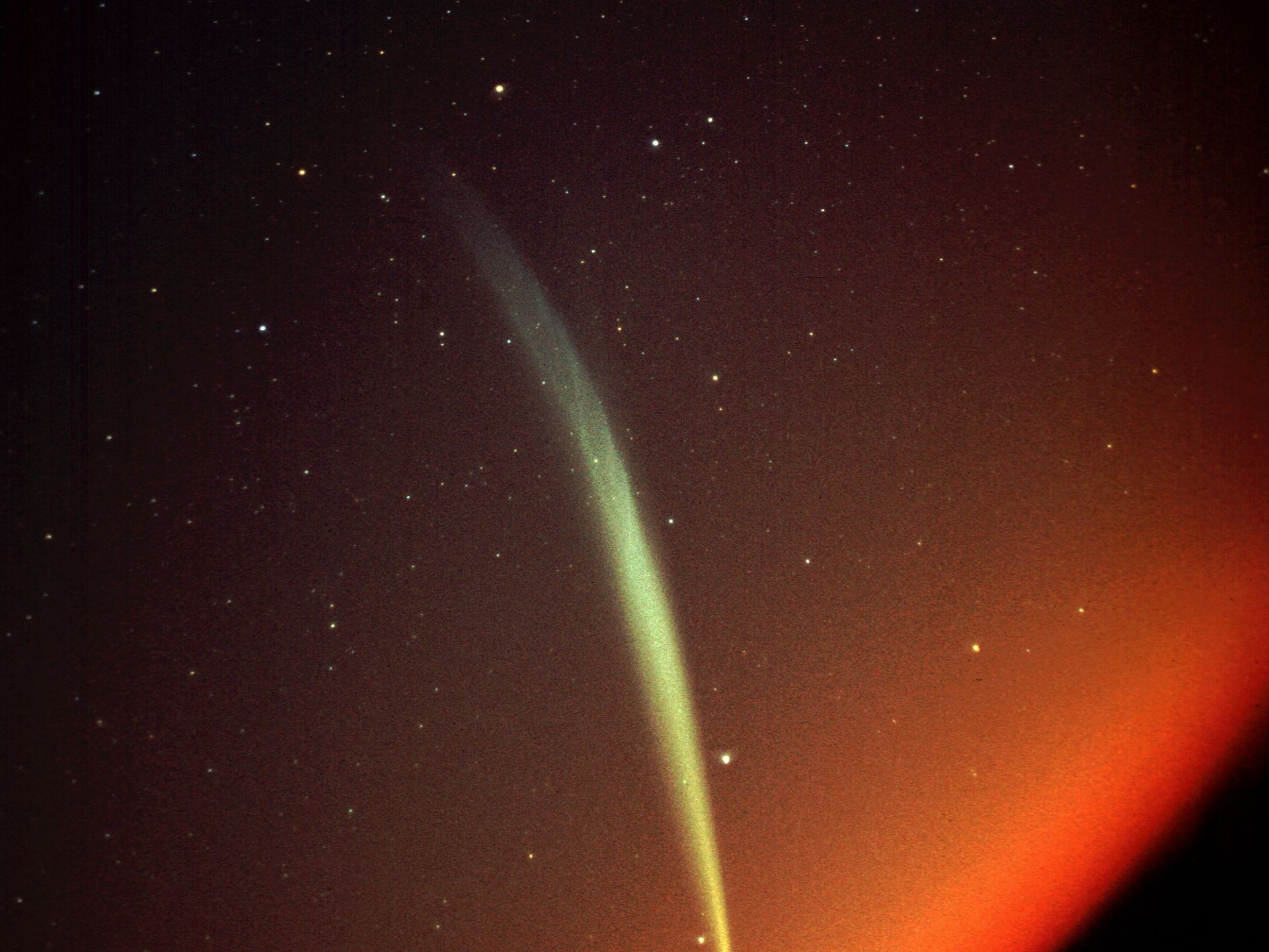 Une traînée de lumière colorée devant un fond d'espace rouge