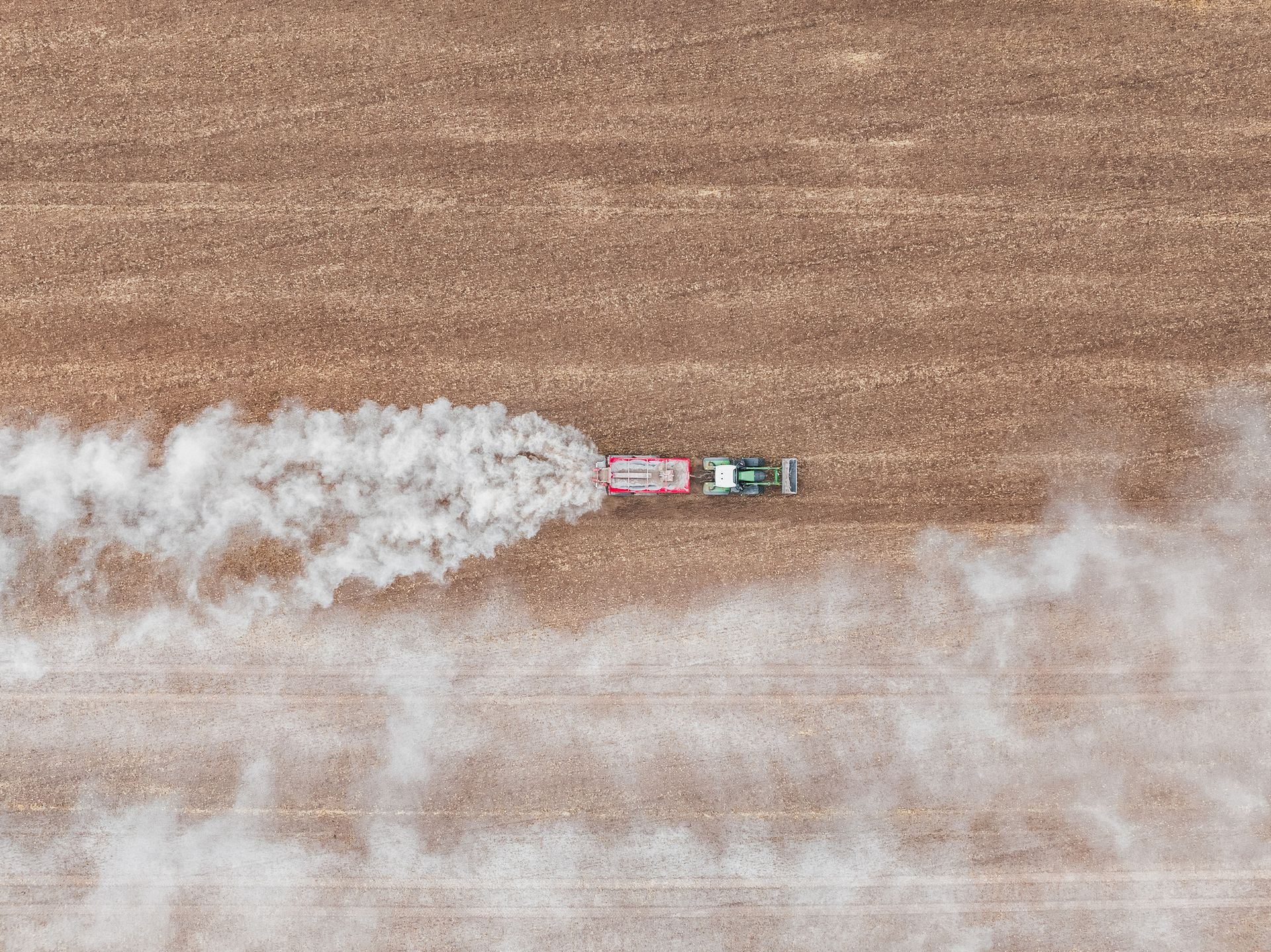 Une photographie aérienne d’un tracteur épandant de l’engrais.