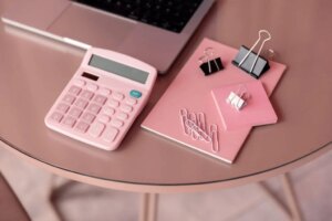 calculatrice rose et carnet sur table