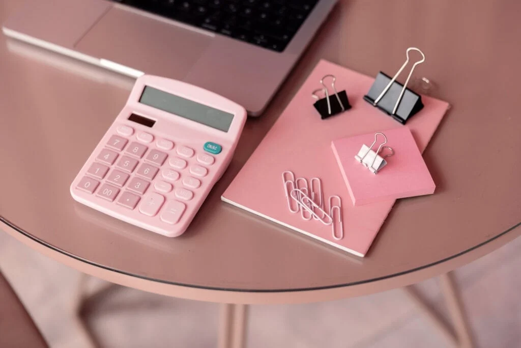 calculatrice rose et carnet sur table