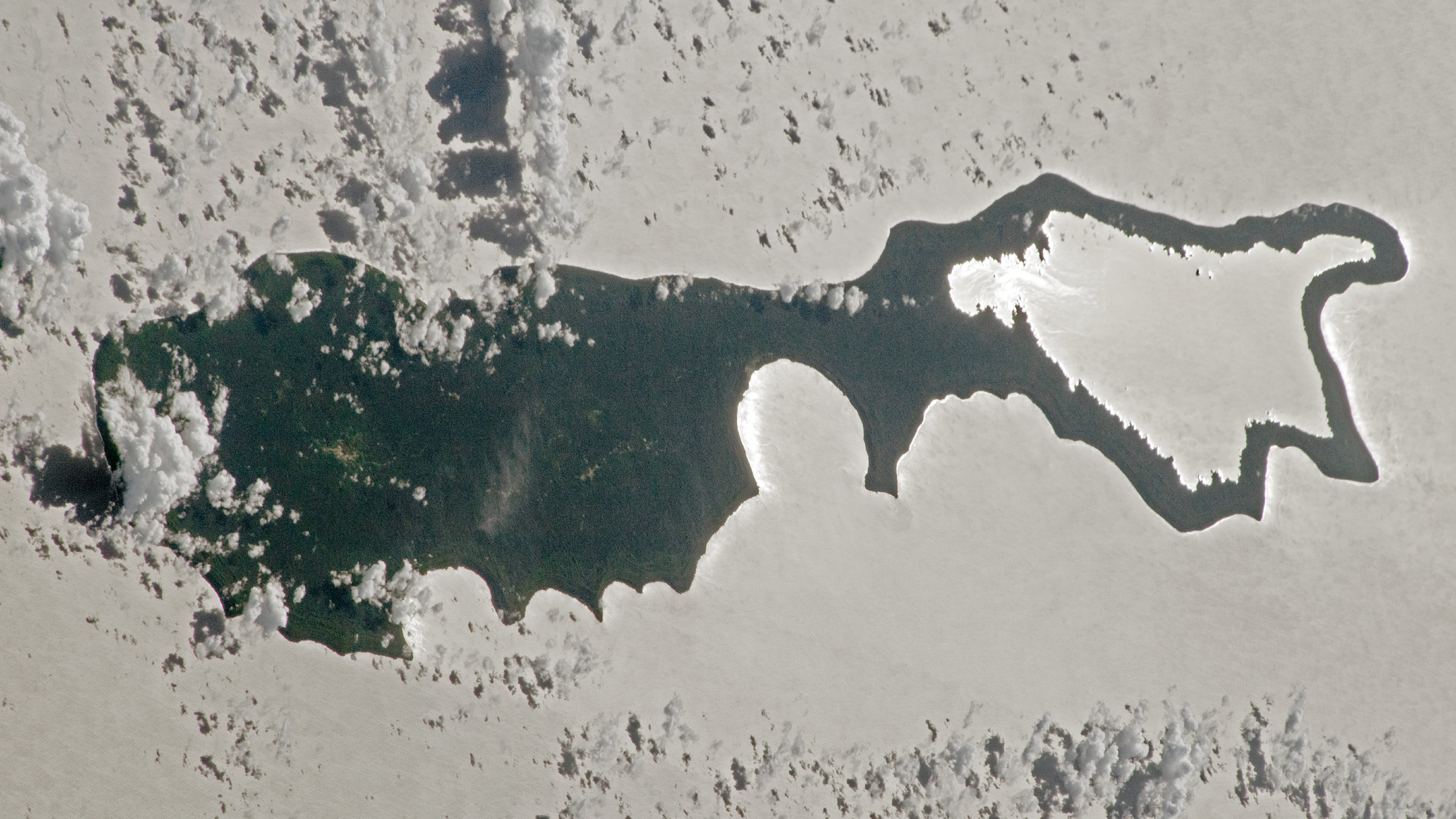 Photo d'un astronaute d'une île avec la lumière du soleil se reflétant sur un lac, faisant ressembler la masse continentale à une loupe