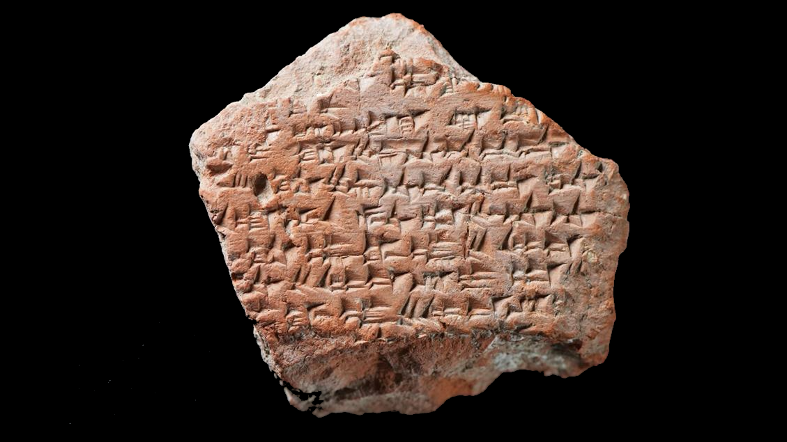 a fragment of light-orange cuneiform tablet against a black background