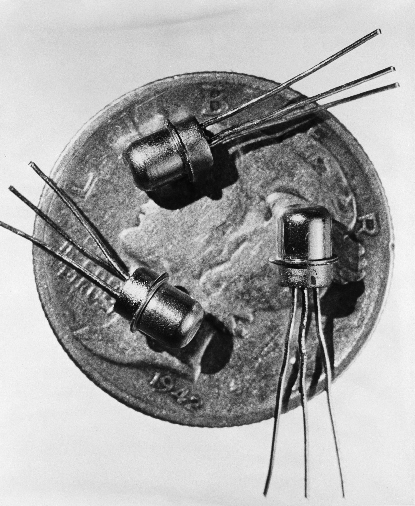 Trois tubes métalliques avec des pointes qui en sortent sont posés sur une pièce de monnaie sur une photo en noir et blanc