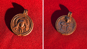 two sides of a copper-alloy pendant on a red fabric background
