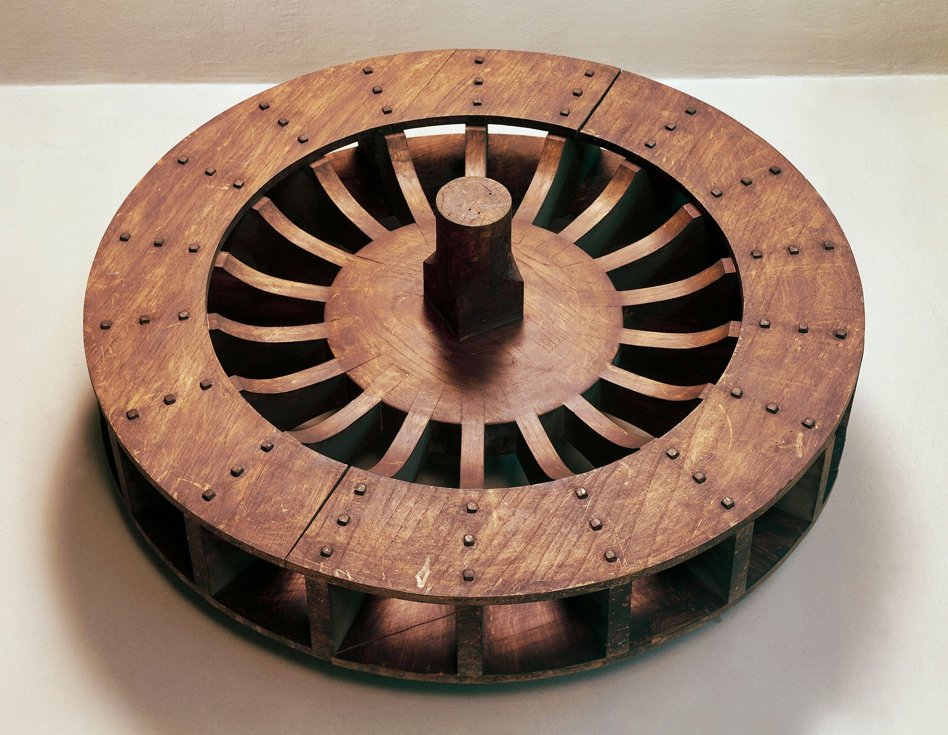 Une grande roue brune repose sur une surface blanche