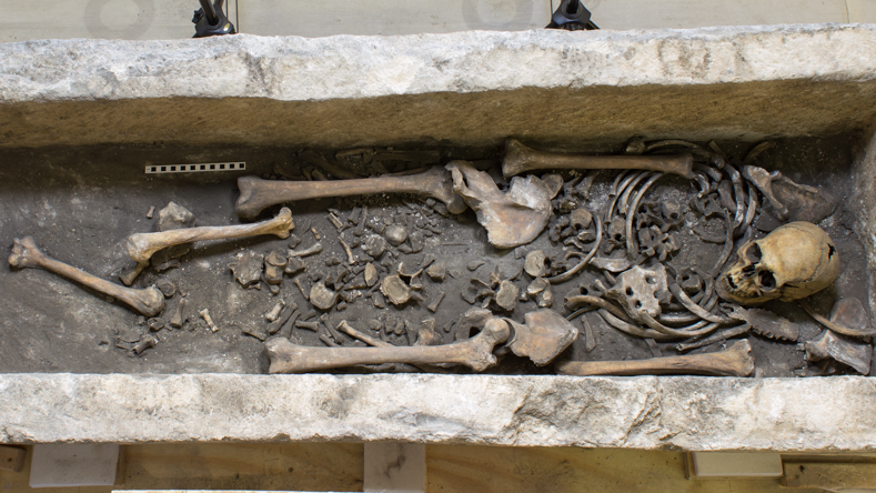un squelette humain entièrement disposé dans un sarcophage mais avec plusieurs os égarés