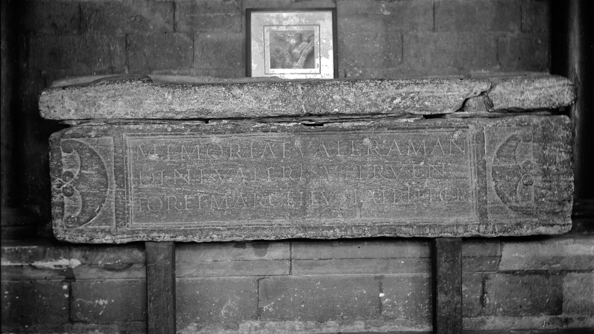 une photographie en noir et blanc du côté d'un sarcophage romain montrant une inscription