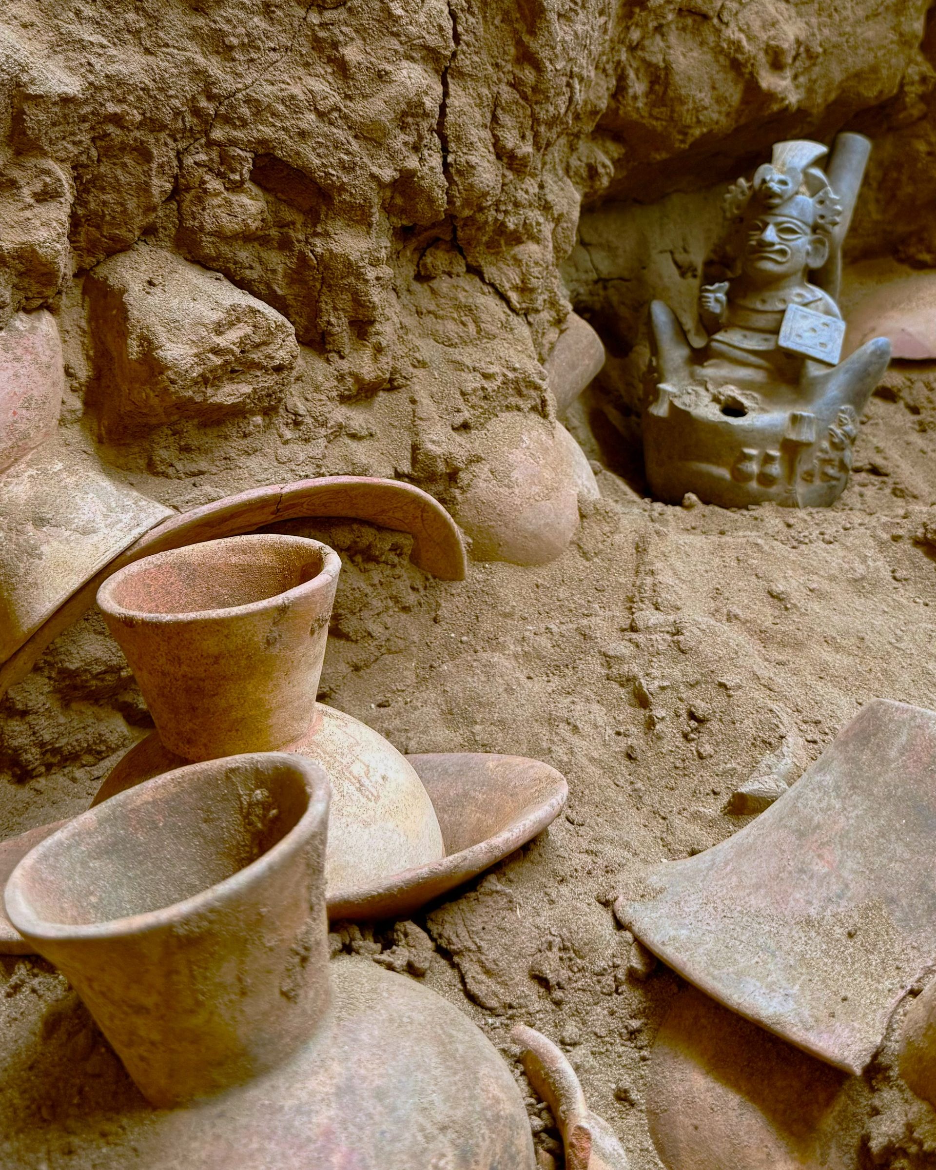 Une série de bols et de vases en céramique sont à moitié découverts dans une grotte.